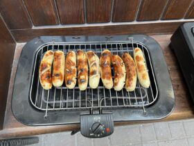 Ein Grill auf dem braun gegrillte Bratwürste liegen