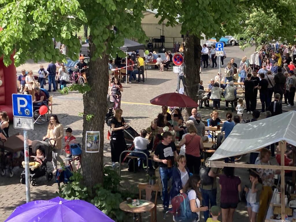 Blick auf das Straßenfest in der Cantianstraße: Viele Menschen, Verkaufsstände, Sitzmöglichkeiten im Schatten